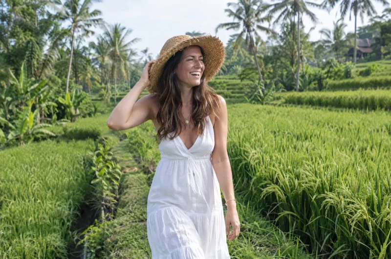 Solo photoshoot in Bali – laughing woman in a straw hat in a rice field near Ubud