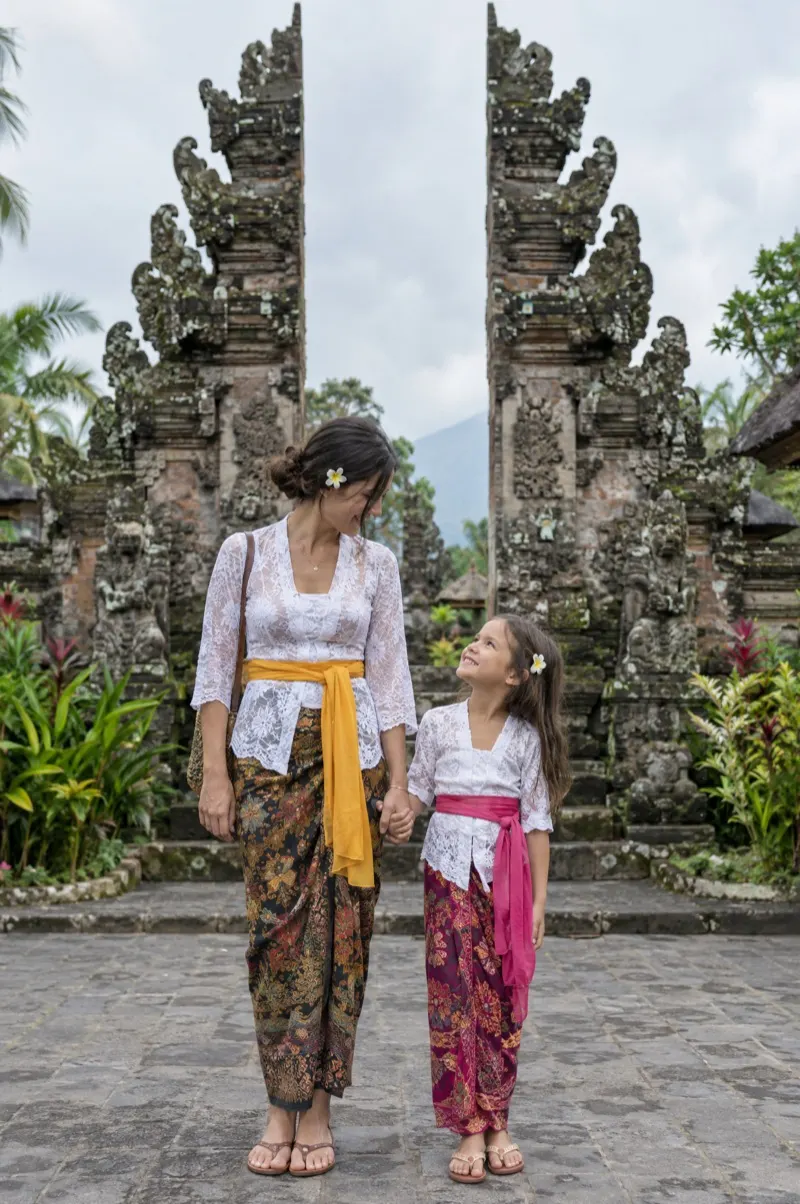 Mother and daughter wearing sarongs in front of a Balinese temple gate