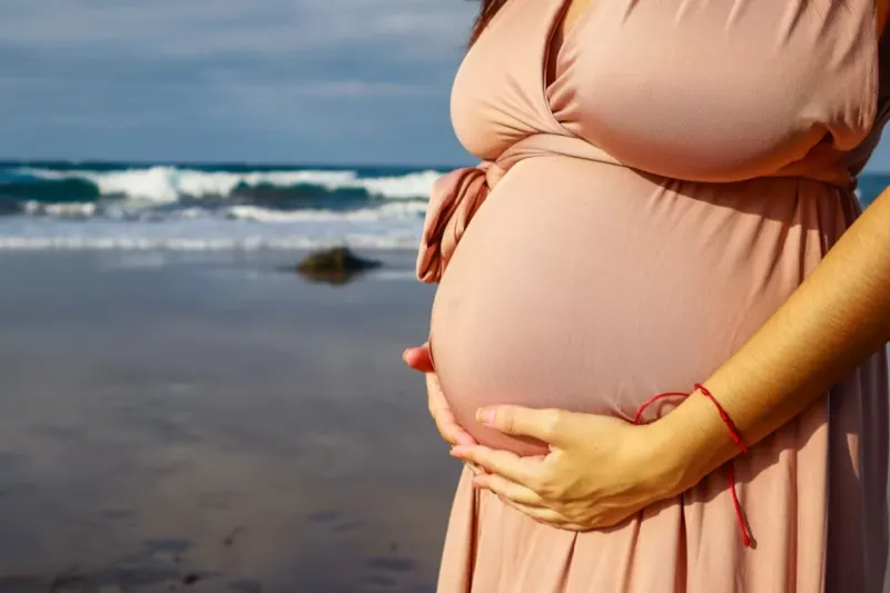 Pregnant woman silhouette against the dramatic sunset sky over the Atlantic