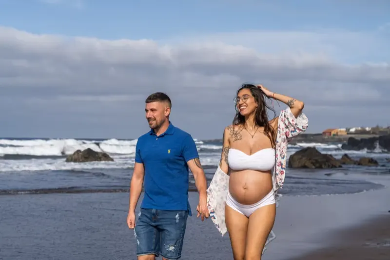 Pregnant woman cradling her baby bump on the golden dunes of Maspalomas in Gran Canaria