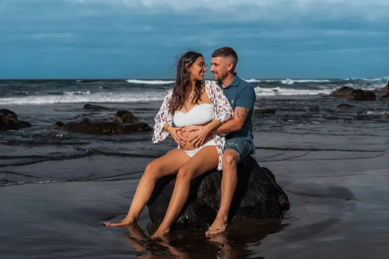 Werdendes Paar sitzt auf einem Felsen am Playa del Inglés
