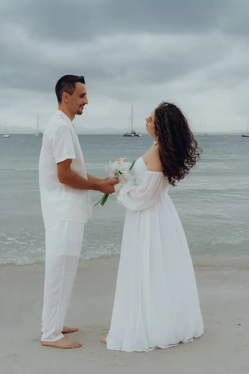 Close-up of wedding rings in the sand with the sea blurred in the background