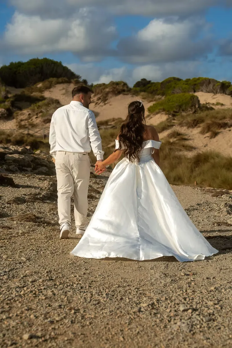 Bride dancing carefree in her wedding dress on the beach at low tide