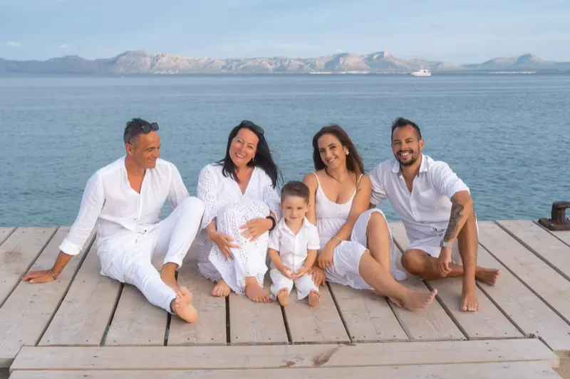 Familie sitzt fröhlich auf dem Holzsteg in Alcudia