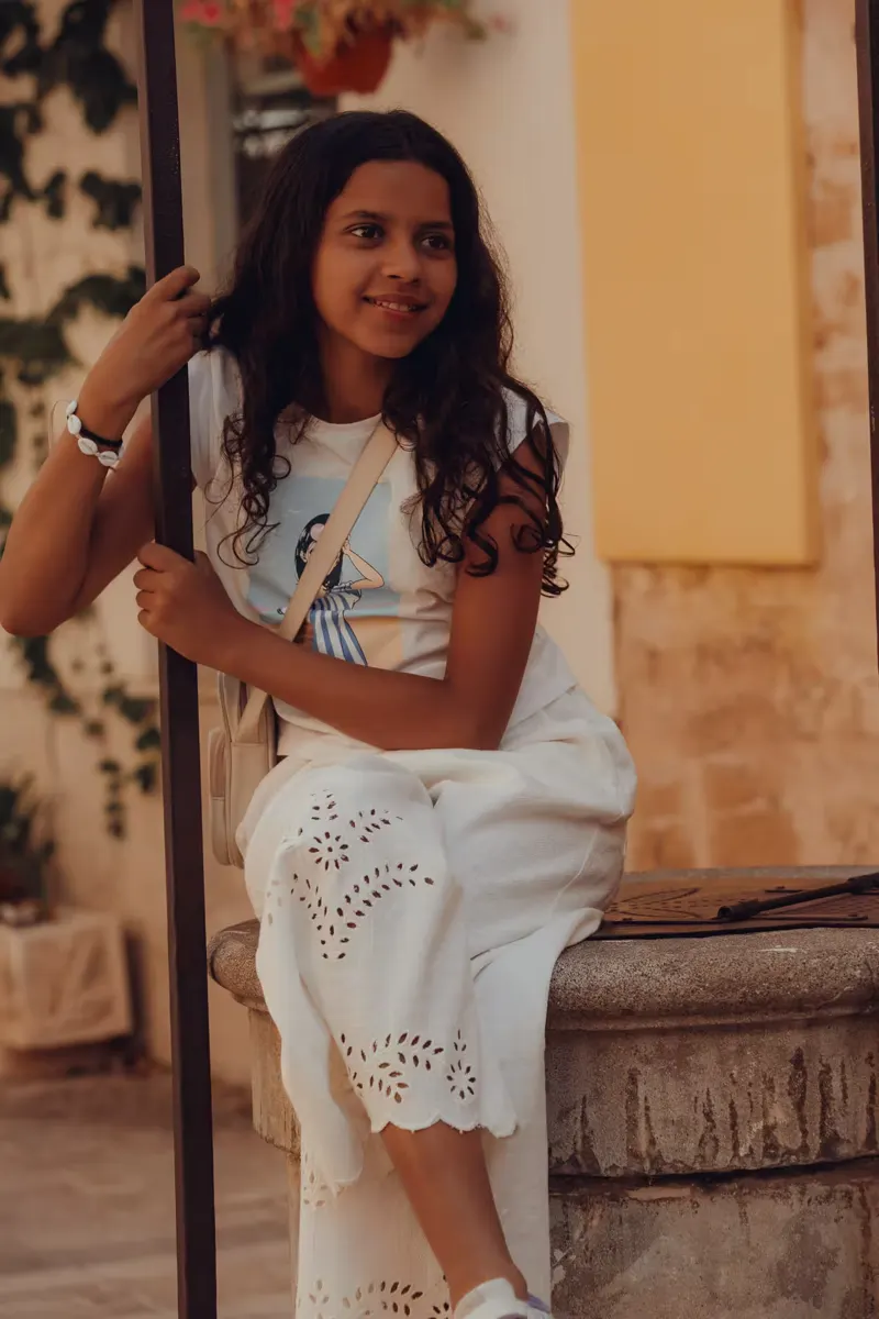 Junges Mädchen sitzt auf einem Brunnen in der Altstadt von Alcudia