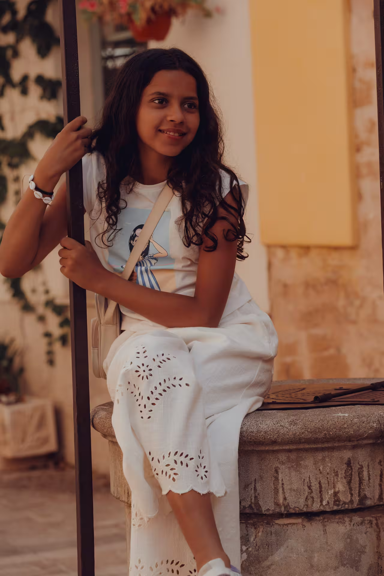Young girl sitting on a fountain in the old town of Alcudia