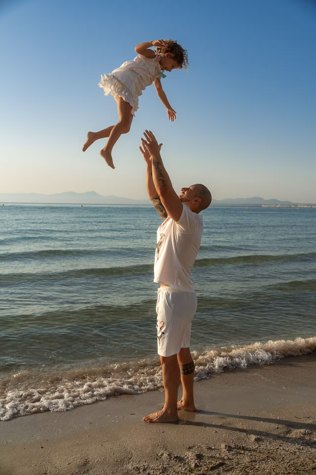 Father tossing his daughter high in the air at the Alcudia photo shoot