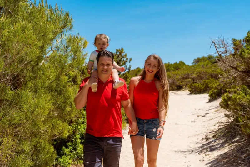 Familie läuft mit Kind auf der Schulter durch die Landschaft bei Cala Millor
