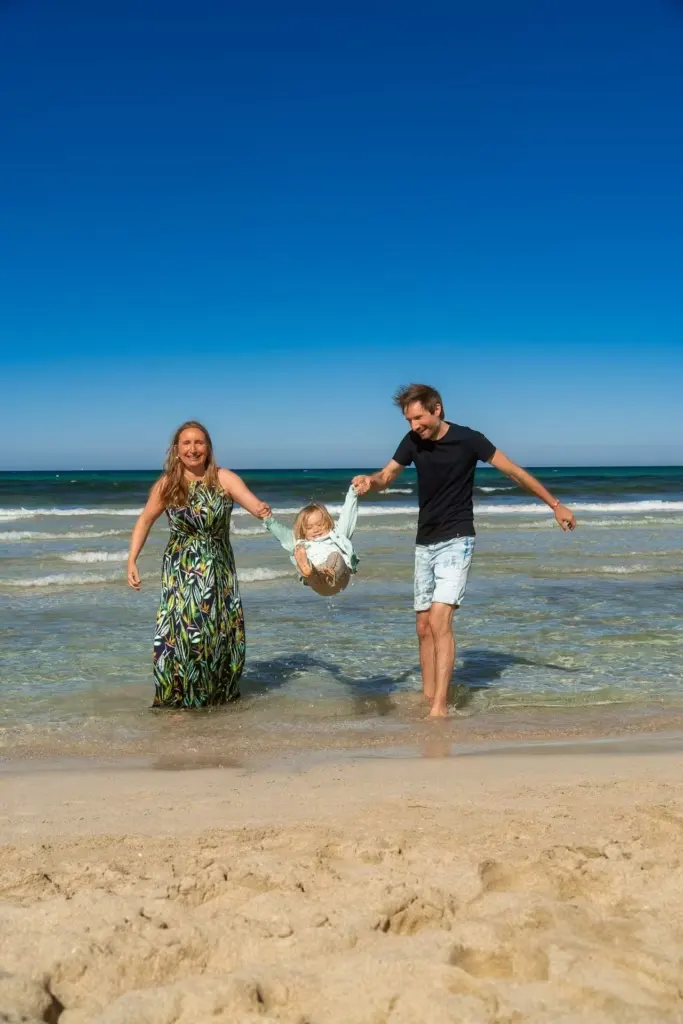 Familie spielt Engelchen flieg mit Kind am Meer von Cala Millor