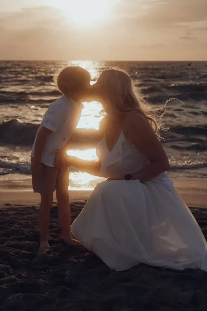 Mutter küsst ihr Kind beim Sonnenaufgang in Cala Millor