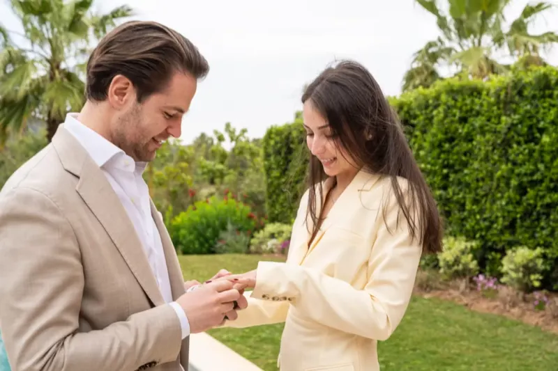 The man placing the engagement ring on his happy partner's finger