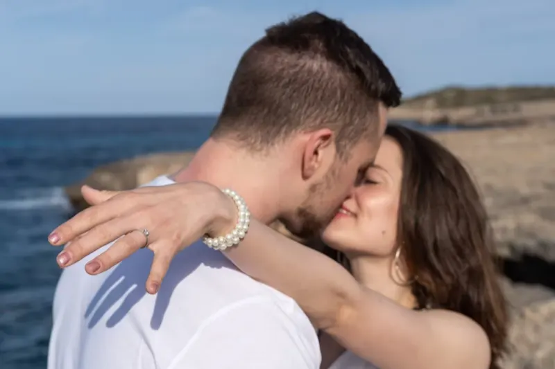 Newly engaged couple kissing passionately at the rocky coast of Mallorca