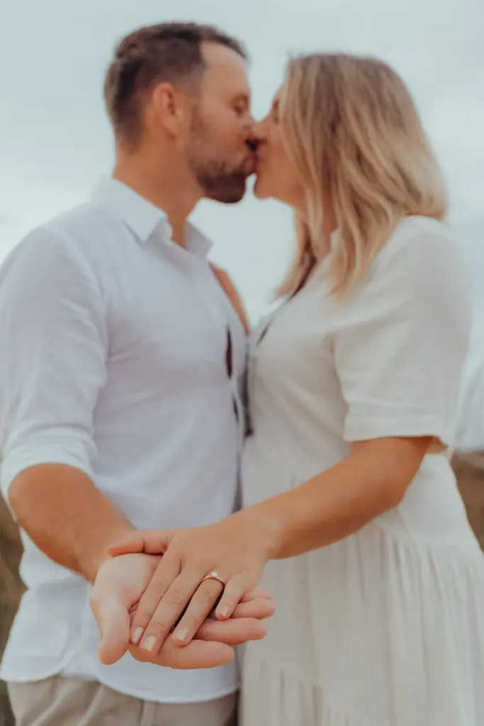 Close-up of a newly engaged couple kissing on the beach