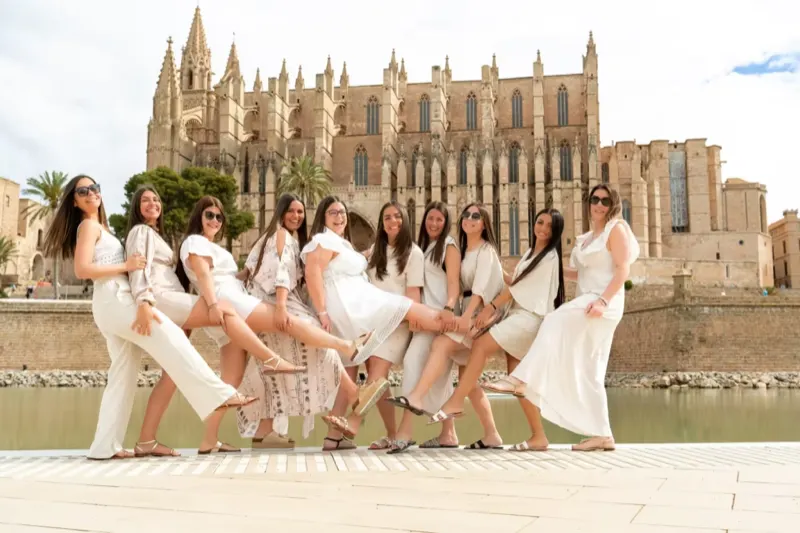 Eine JGA-Gruppe in weißen Outfits posiert vor der berühmten Kathedrale von Palma