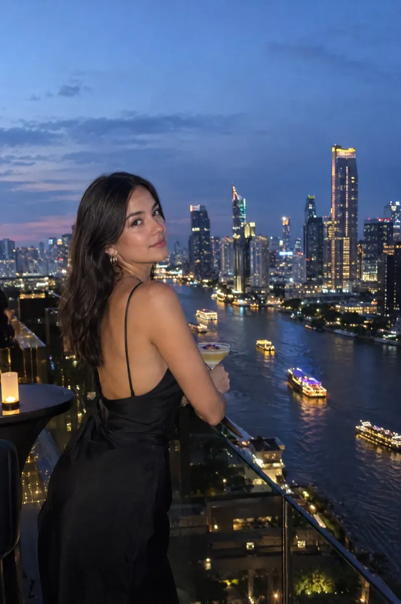 Frau im Abendkleid auf einer Rooftop-Bar über der Skyline von Bangkok