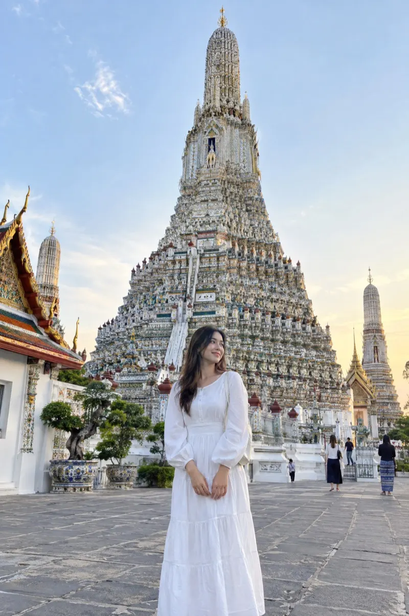 Frau im langen weißen Kleid vor dem Tempel Wat Arun in Bangkok
