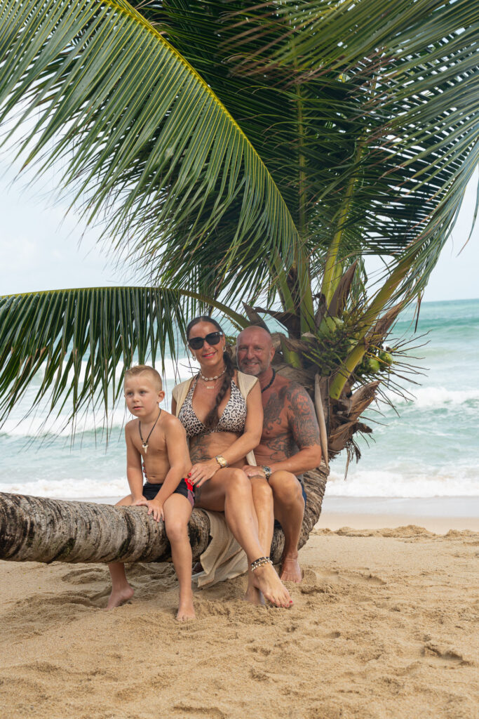 Family photo shoot Thailand – couple with son on a palm tree on the beach