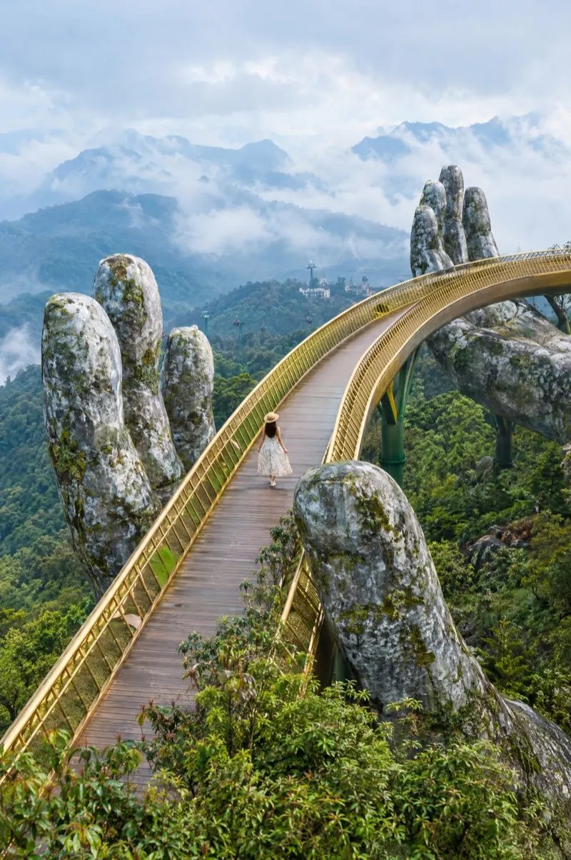 Woman on the Golden Bridge held by giant stone hands in the Ba Na Hills near Da Nang