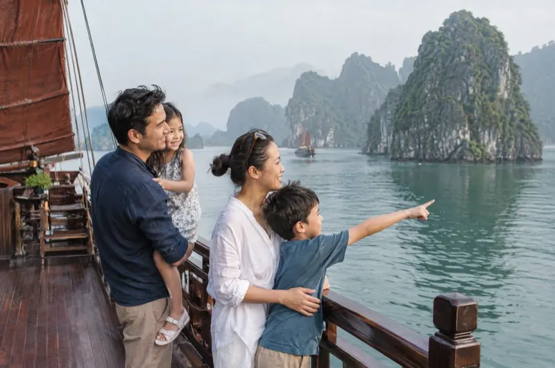 Family on the deck of a junk boat in front of the limestone islands of Ha Long Bay