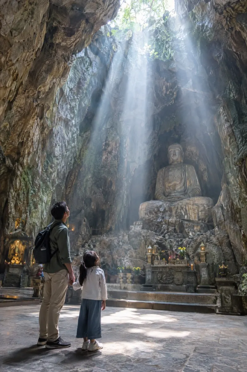 Father and daughter in Huyen Khong cave at the Marble Mountains with beams of light
