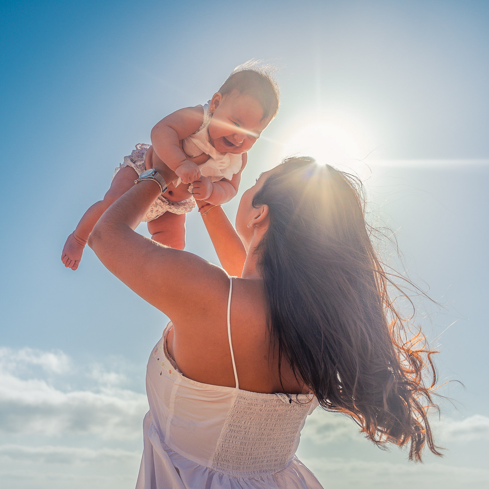 Urlaubs Fotoshooting Mutter hält fröhlich ihr Baby in die Luft