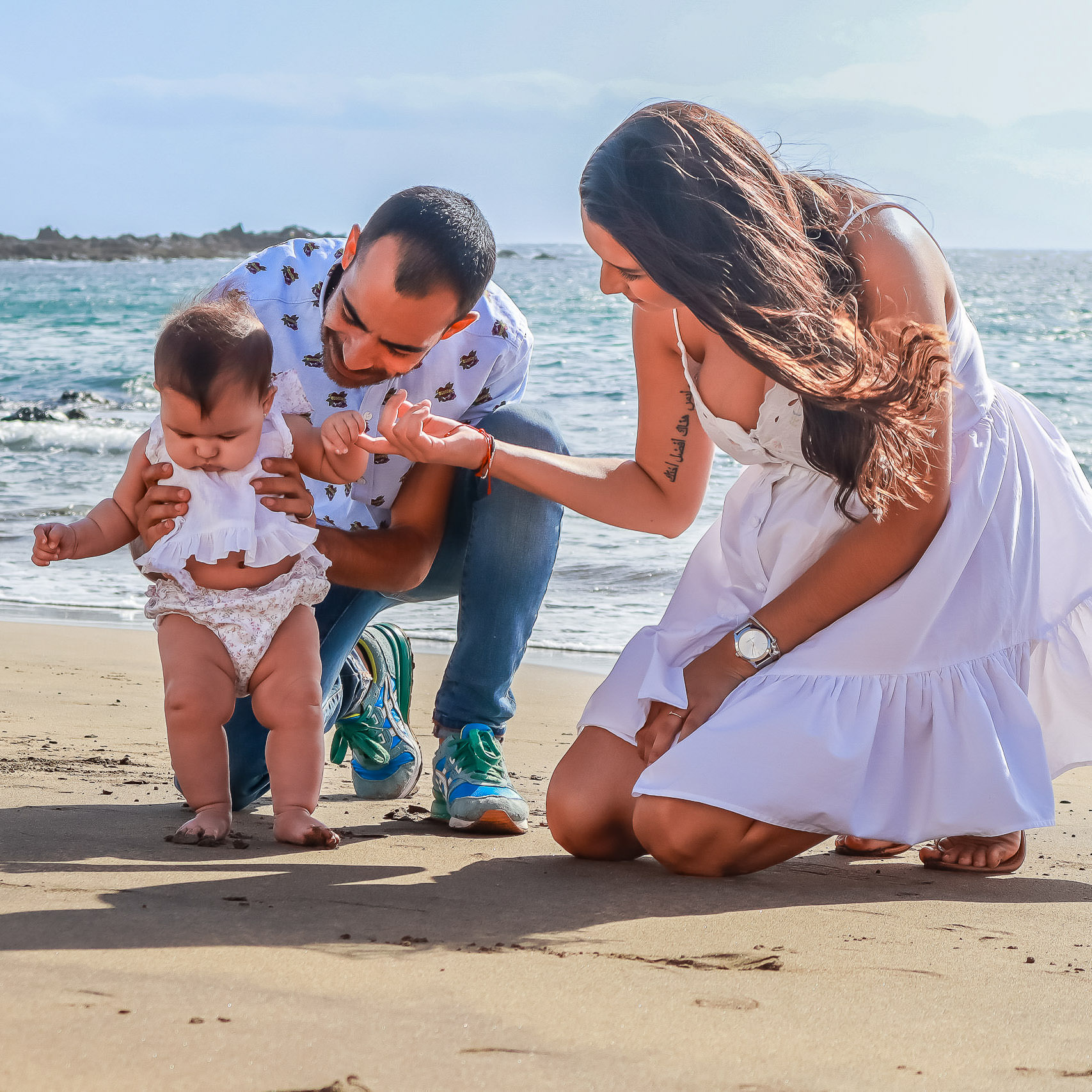Urlaubs Fotoshooting Junge Familie stellt ihr Baby das erste mal mit den Füßen im Sand