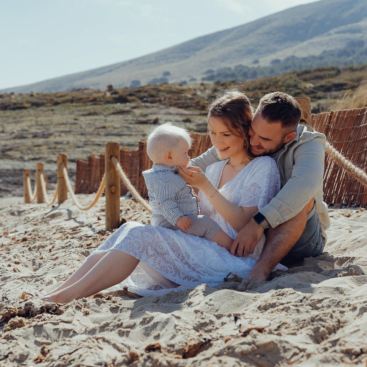 Urlaubs Fotoshooting Junge Familie mit Baby sitzt im Samd am Meer