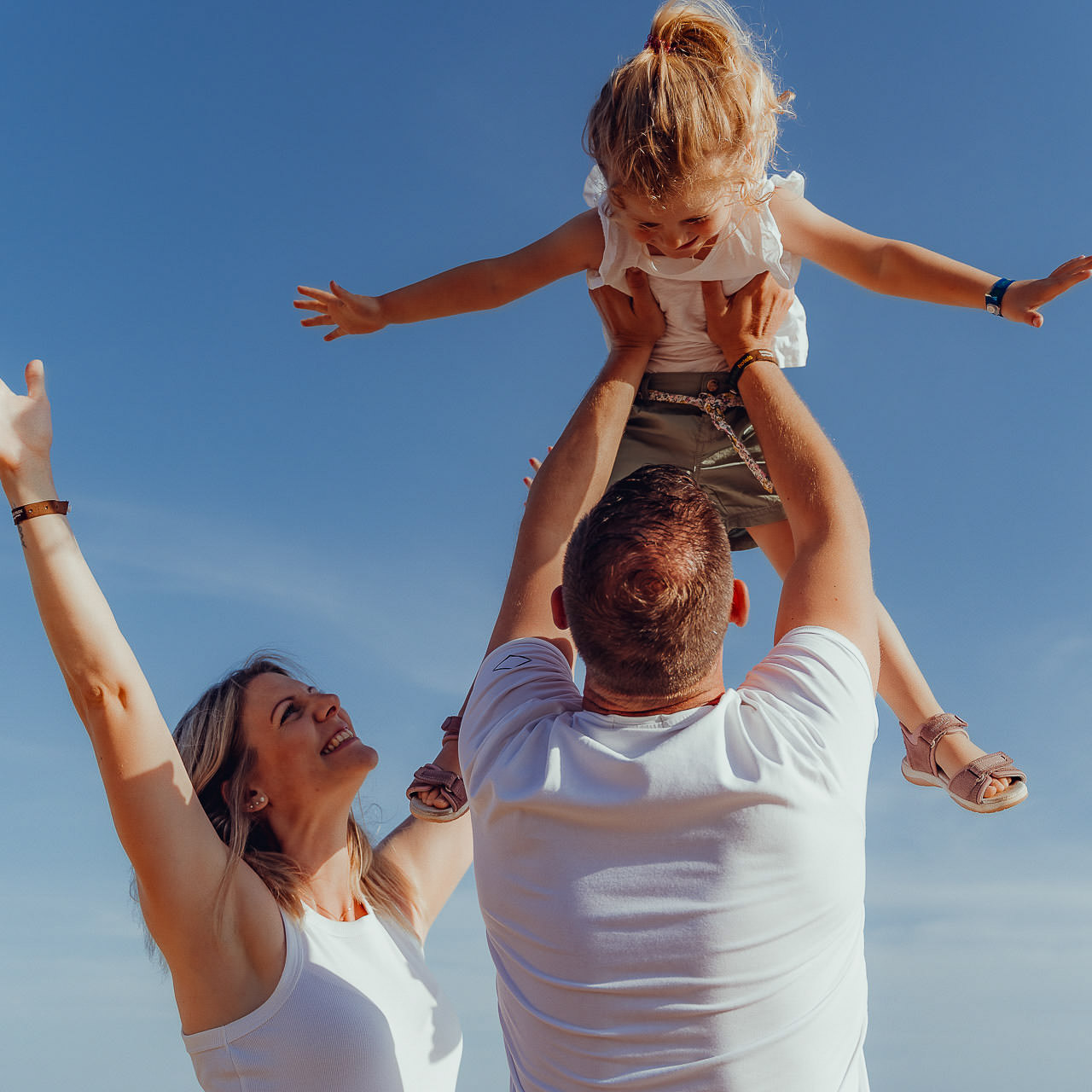 Urlaubs Fotoshooting Vater hebt seine Tochter hoch in die Luft