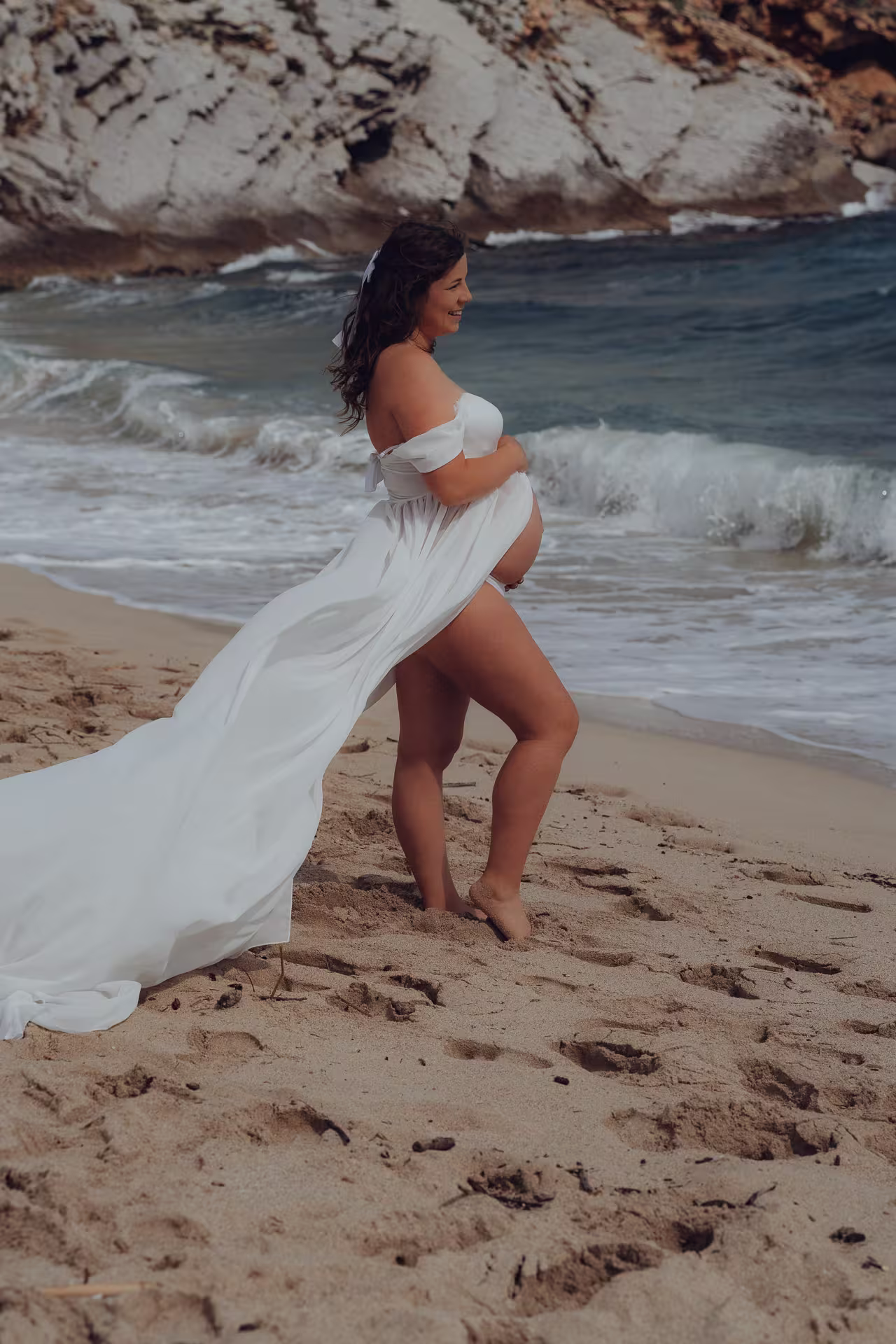 Ibiza-017-www.urlaubsfotoshooting.com Schwangerschafts Fotoshooting auf Ibiza am Strand – werdende Mutter im weißen Kleid, elegante Aufnahme mit Meereskulisse vom Ibiza Fotograf.