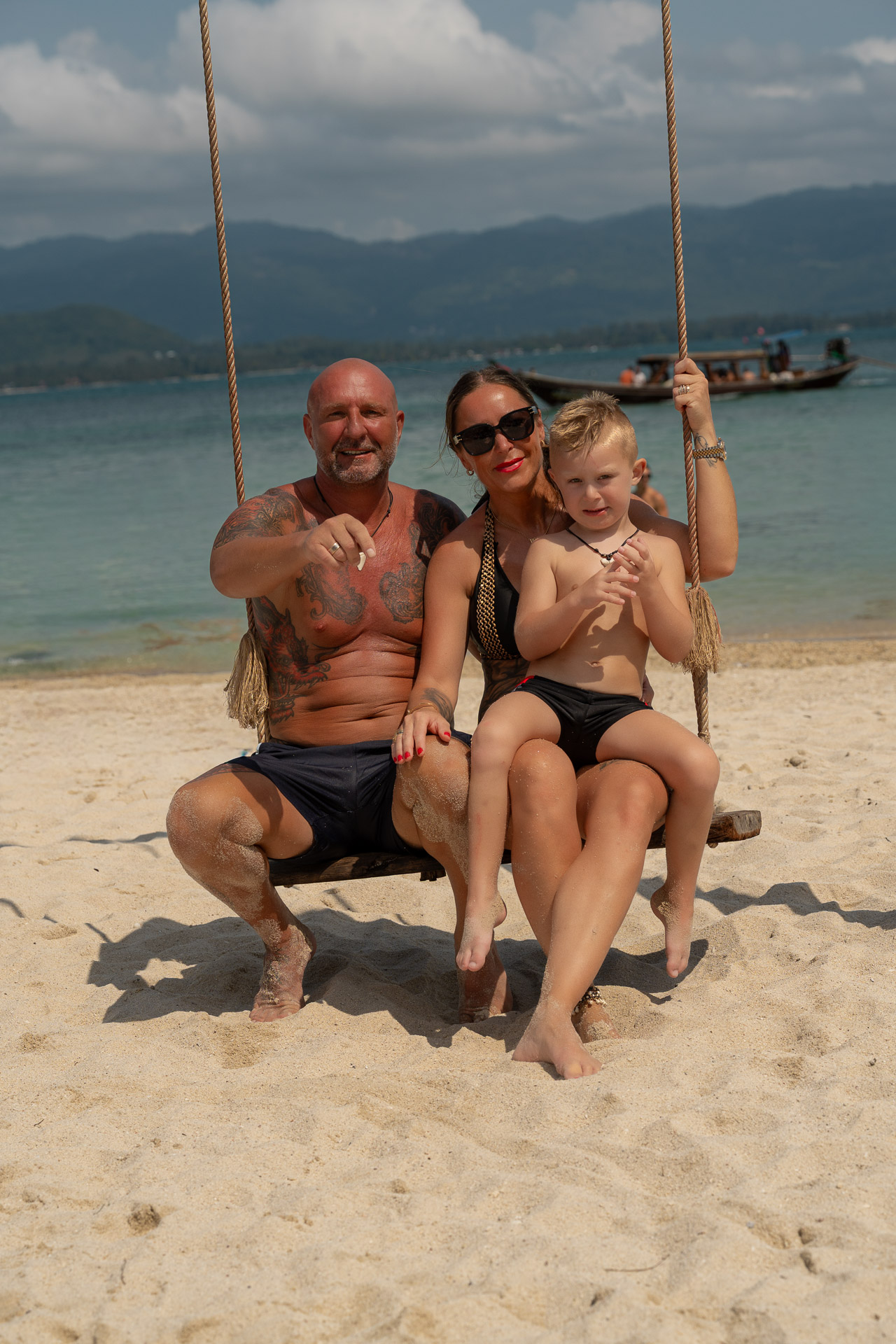 Familienfotoshooting Thailand – Familie auf Schaukel am Strand, entspannte Urlaubsstimmung mit Meerblick, aufgenommen von Thailand Fotograf.
