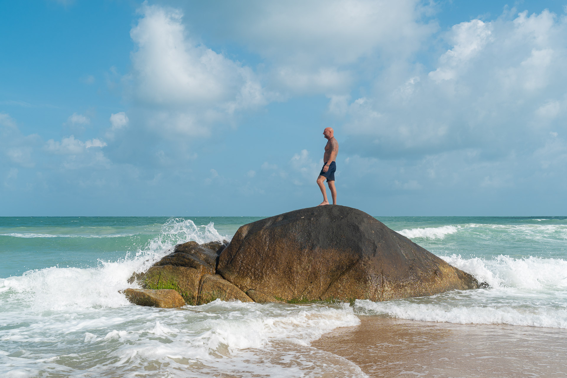 Thailand Urlaubs Fotoshooting am Meer – Mann steht auf Felsen mit Blick auf den Ozean, dynamische Aufnahme vom Thailand Fotograf.