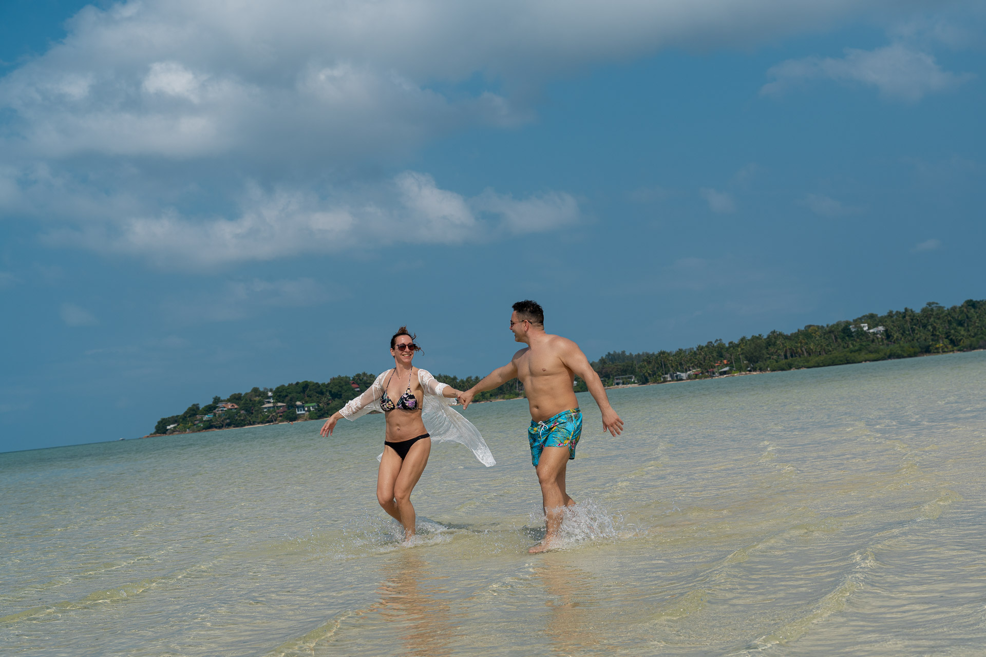 Verliebtes Paar beim Thailand Fotoshooting – natürliche Aufnahme beim Laufen im flachen Wasser, festgehalten vom Thailand Fotograf.